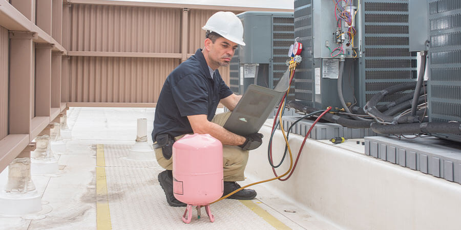 Service technician checking commercial HVAC units on the roof